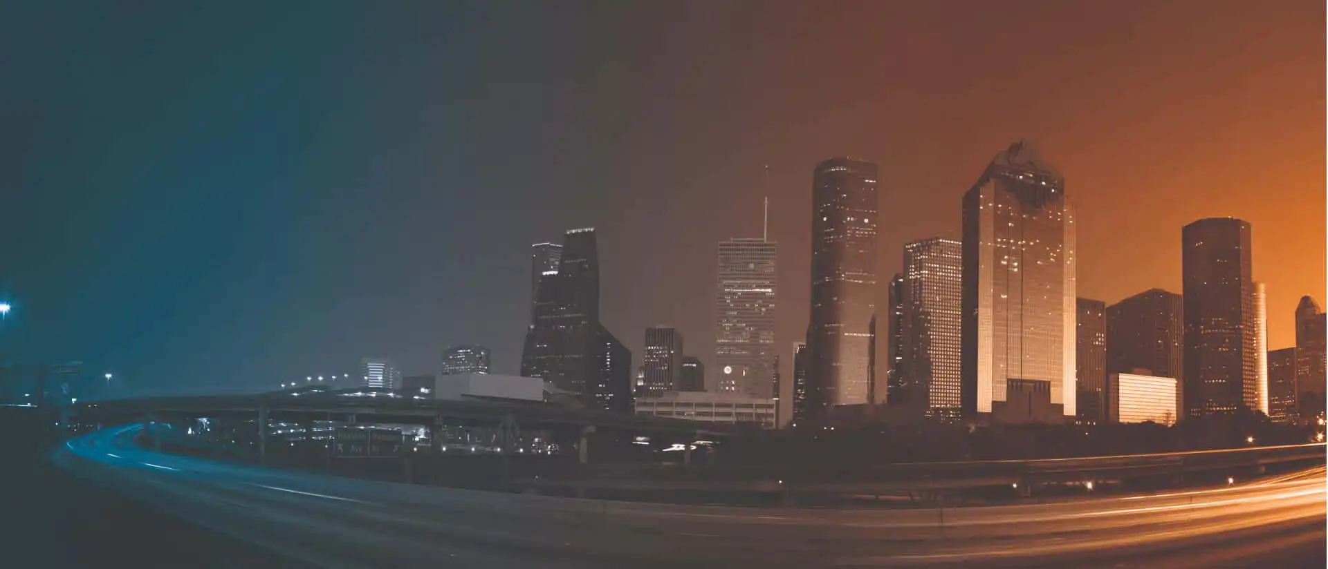 A city scape with a overlay of the brand colours and a highway in-front of the city